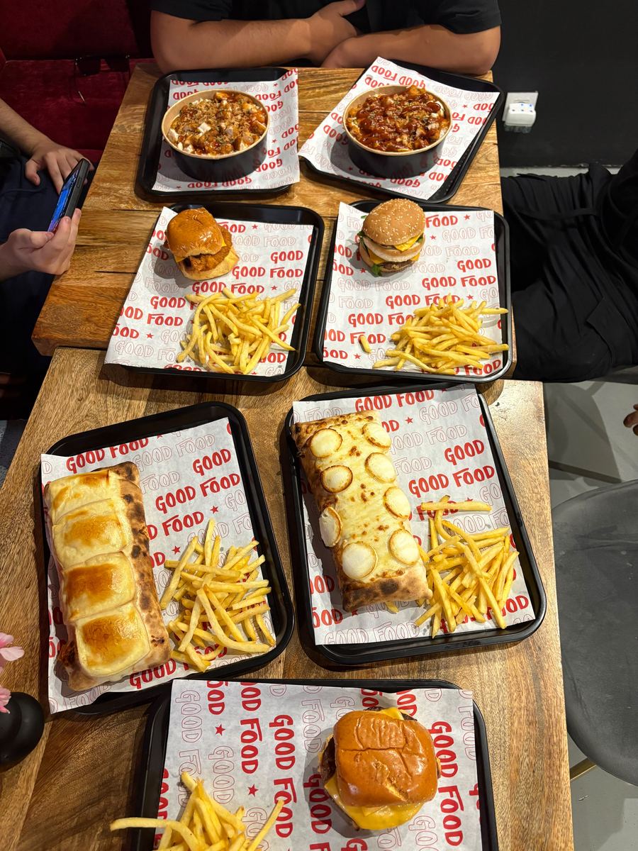 Grupo de amigos disfrutando de una mesa llena de tacos y burgers de La Firma